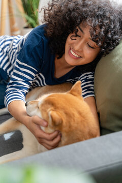 woman cuddling with shiba inu dog on sofa