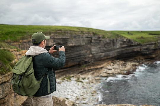 Man photographing cliffs in the sea with his mobile phone