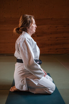 Woman Kneeling on matt wearing Aikido Gi