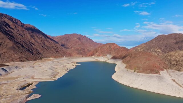 Aerial view captures Orto Tokoy reservoir and dam surrounded by mountains in Kyrgyzstan. Autumn 2025.