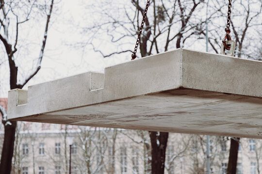 Low-angle view of a prefabricated concrete slab suspended during crane installation. Structural precast element highlighting strength and precision engineering.