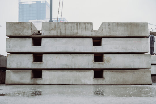 Stack of prefabricated concrete slabs arranged in an industrial storage area. Heavy precast elements used in infrastructure and urban construction projects.