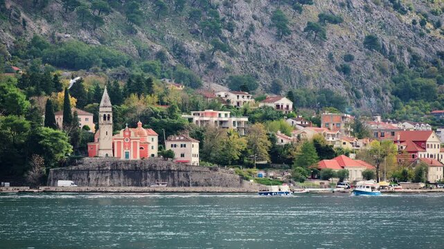 St. Eustace Church sitting on an elevated fortified wall along the Kotor Bay waterfront with mountains