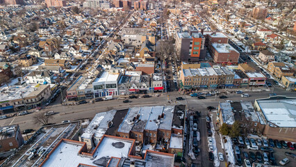 Aerial view capturing a new york city neighborhood street with a mix of residential homes and commercial buildings, featuring vehicles navigating roads and snow dusted rooftops during winter © contentzilla