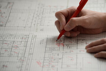 製図図面を赤ペンでチェックする手元 建築設計の修正作業Hand checking architectural drawing with red pen