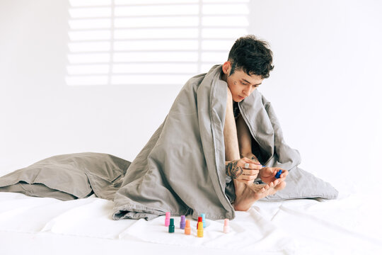 Man Painting Nails in Bright Bedroom Morning