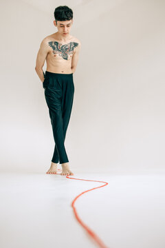 Young Man With Tattoo Following Red String Indoors