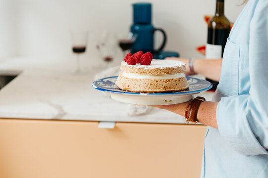 Woman holding a cream and raspberry cake