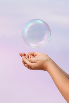 Hands of kid folded together and catching transparent air bubble