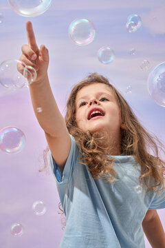Excited baby reaching out with finger for bursting soap bubble