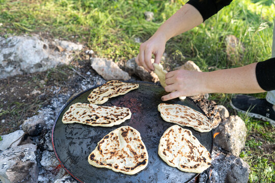Woman Baking Flatbread Over Open Fire