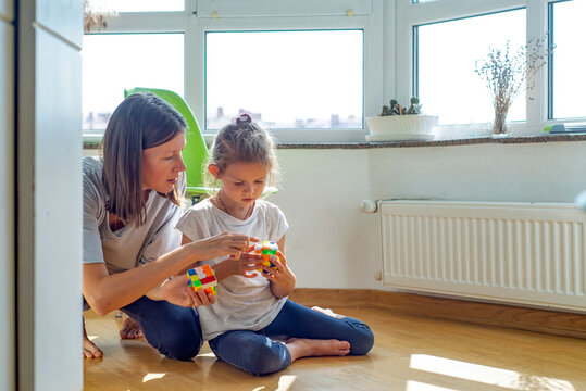 young female babysitter plays with a child with a toy at home