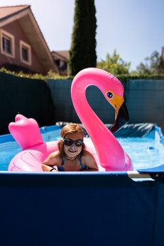 Young girl wearing goggles and playing with inflatable flamingo