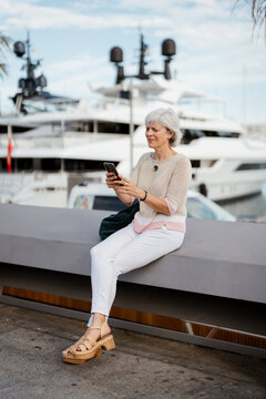 A woman sits on a bench in the city and uses her cellphone