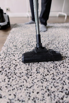 Cropped view of person cleaning carpet with vacuum cleaner at home