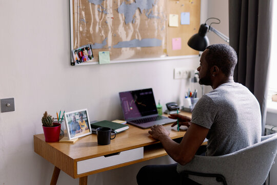 Concentrated adult black man watching stock market graph on laptop