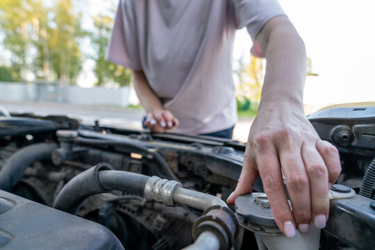 Woman Closing Car Fluid Reservoir Cap Under Hood
