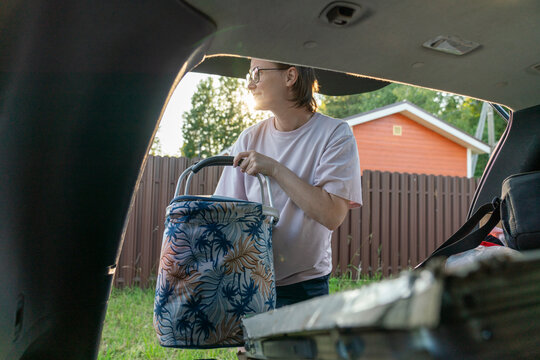 Woman Loading Patterned Bag into Car Trunk