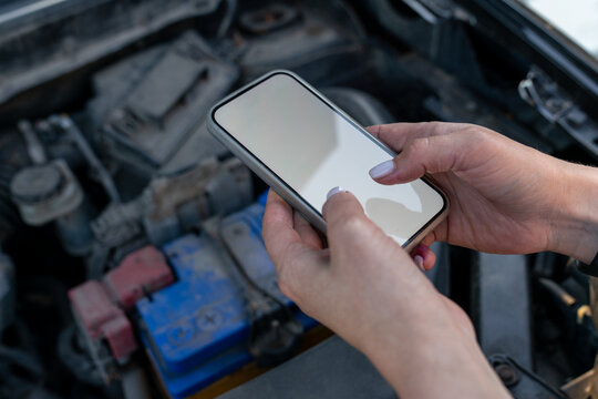 Using a smartphone to photograph a car engine.