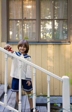 A child in a sailor outfit plays happily on the porch steps 