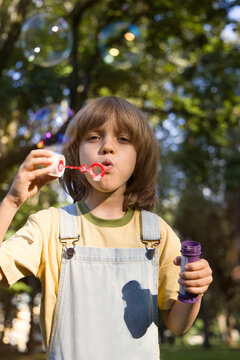 A Child Enjoys Blowing Bubbles in a Sunlit Park 