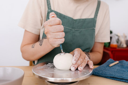Crop artisan using tool on clay