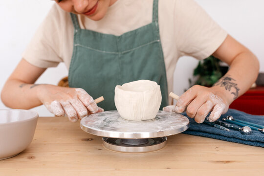 Faceless craftswoman making clay bowl