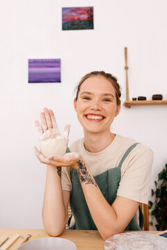 Portrait of female artisan with hands dipped in clay