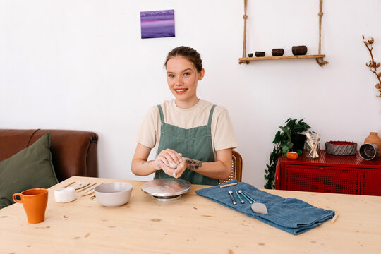 Cheerful woman with clay in hands