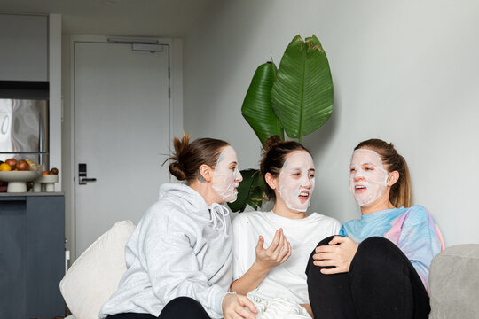 Three women relaxing with facial masks on the couch.