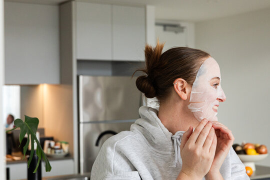 Person in hoodie sitting in modern kitchen holding cup