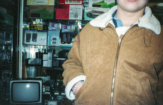 film image of a young man next to an electronics store in the 90s