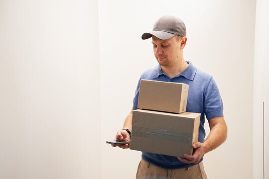 Man Holding Boxes While Using Smartphone Inside Room
