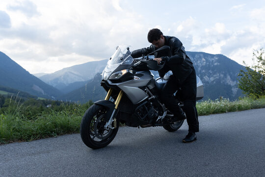 Man parks sport tour motorcycle on mountain pass.
