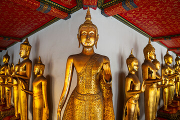 Obraz premium Row of golden standing Buddha statues in the cloisters at Wat Pho in Bangkok