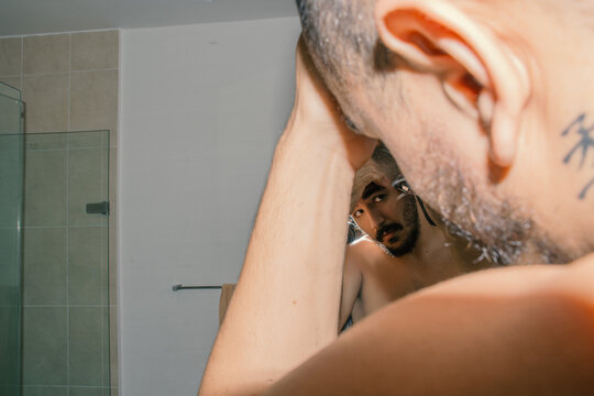 Reflection of bald man giving himself a hair cut