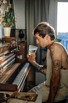 A musician with a glass of water in his studio
