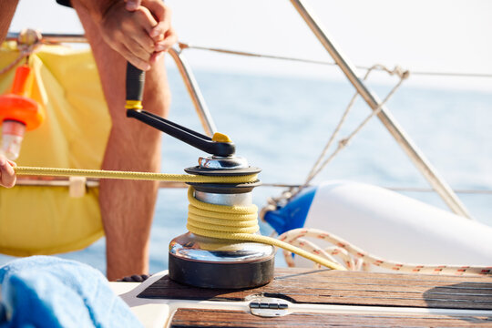 Close up of a man winding the sail rope