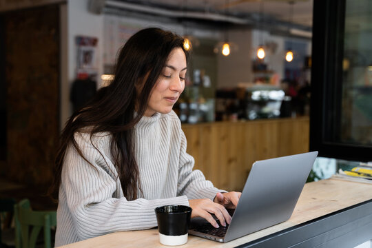 A woman teleworking with a computer in a coffee shop