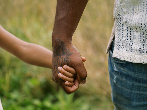 cute moment of black father and daughter holding hands