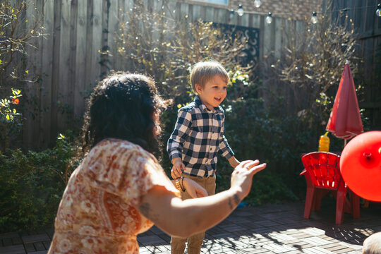 Mother and son playing with a balloon in the backyard
