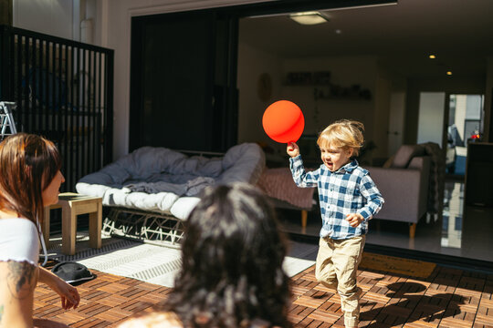 Child running in the backyard playing with a balloon