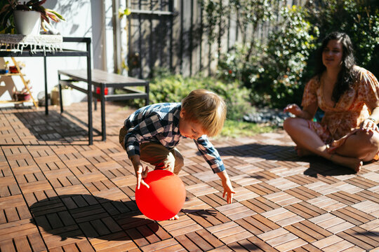 Toddler playing with a balloon with their mother in the backyard