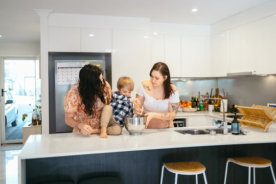 Mothers teaching their young son how to cook