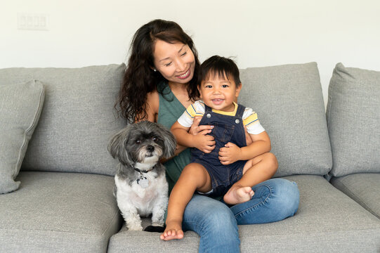 Mom snuggles her son with dog