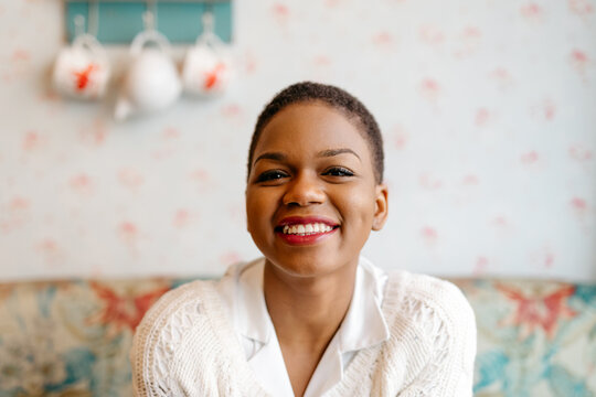 Smiling young Black woman sitting in cozy room