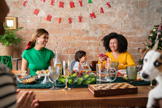 Woman holding received present at Christmas dinner indoors