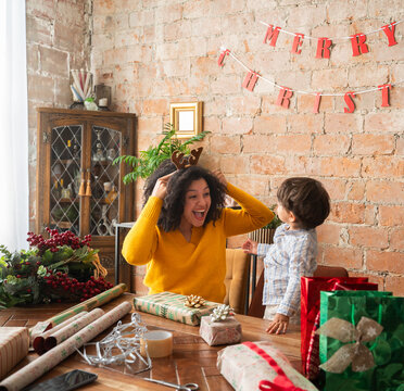 Child looking curious while mother wearing reindeer headband 