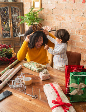 Child looking curious while mother wearing reindeer headband 