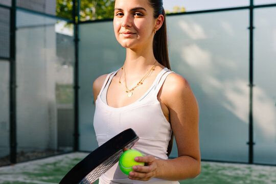 Amateur paddle tennis athlete happily posing with a racket and ball